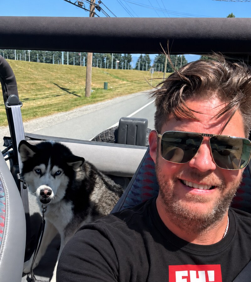 EH! Community Manager Jamie enjoying a sunny drive with his Husky while wearing a black EH! T-shirt
